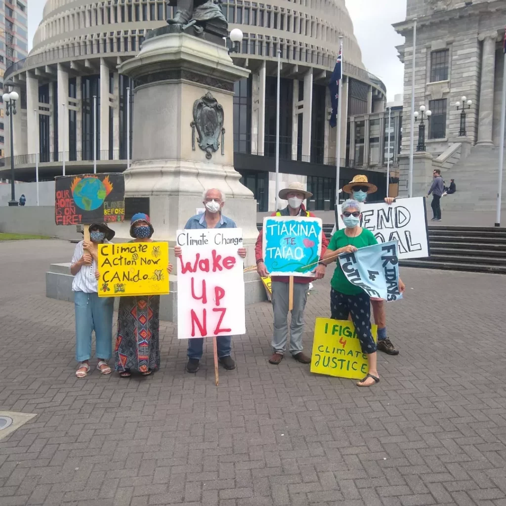 Photo of six members of Fridays for Future Aotearoa, standing in front of the statue of Seddon in front of Parliament, holding placards calling for urgent climate action 